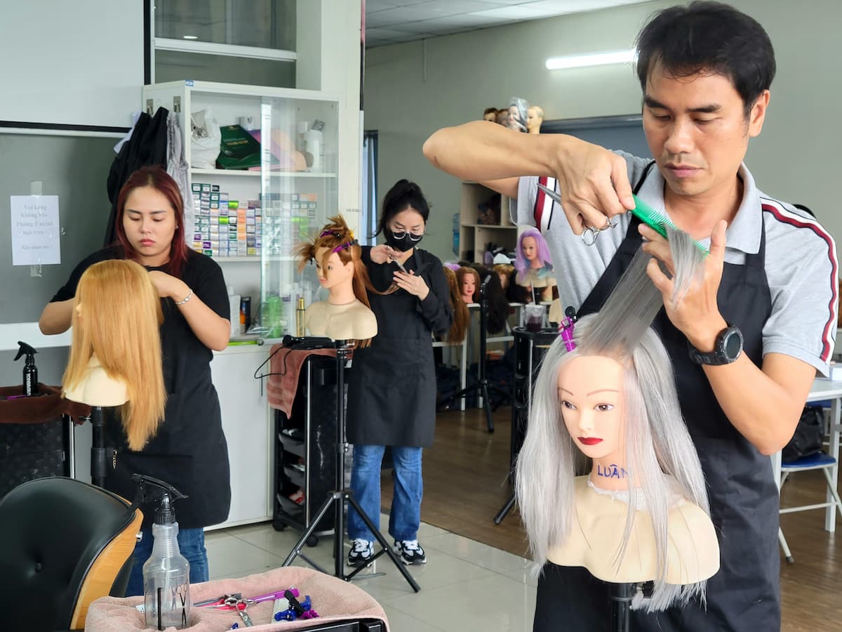Học viên khóa học Tóc chuyên nghiệp tại Jasmine Beauty School đang thực hành kỹ thuật cắt tóc trên mannequin trong lớp học.