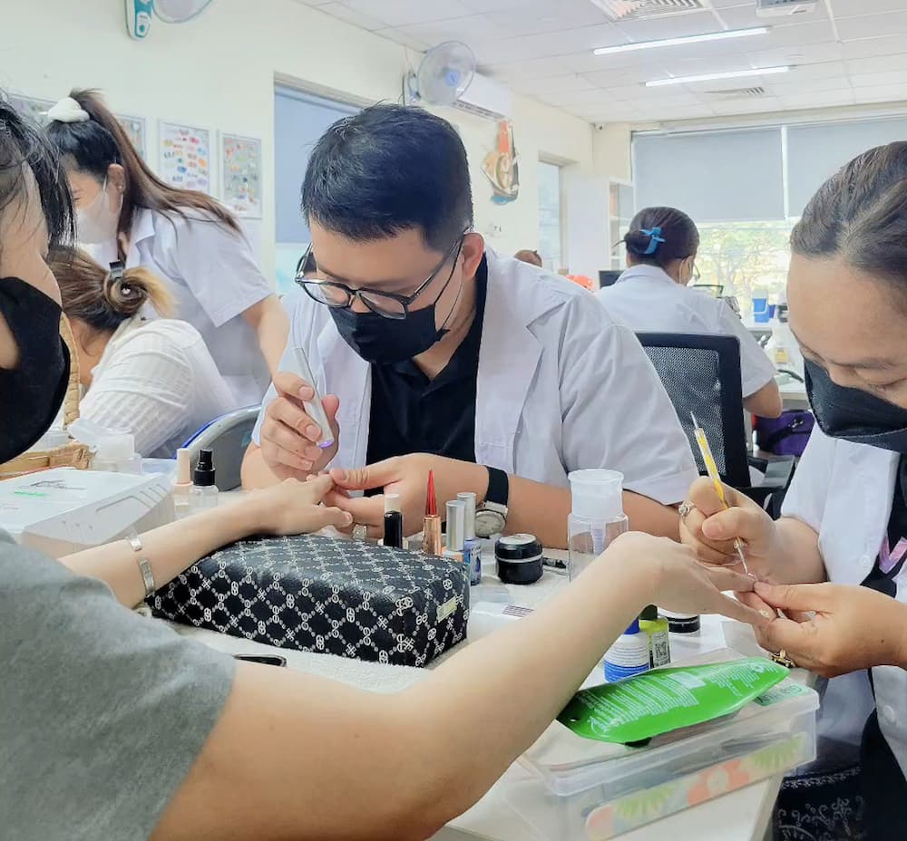 Học viên sử dụng cọ chấm bi để tạo họa tiết tròn trên móng thật