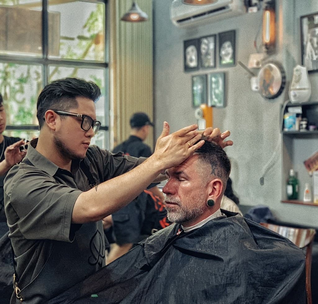 Hình ảnh thợ barber đang cắt tóc nam, minh họa cho quy định thi barber tại mỹ với kỹ năng thực hành chuyên sâu.