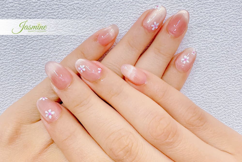 Mẫu nail ombre tự nhiên cho người mới học – sử dụng kỹ thuật sơn loang trắng sữa và vẽ hoa mini trên nền móng oval ngắn.